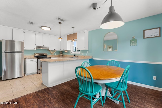 4004 E 7th Cir, Panama City, FL 32404 - kitchen with stainless steel appliances, under cabinet range hood, white cabinetry, a peninsula, and light wood-style floors