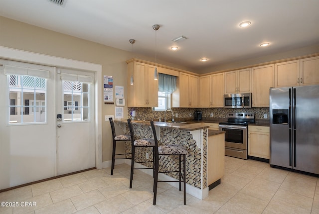 8410 Thomas Dr Unit 1, Panama City Beach, FL 32408 - kitchen featuring appliances with stainless steel finishes, dark countertops, a peninsula, light brown cabinetry, and decorative backsplash