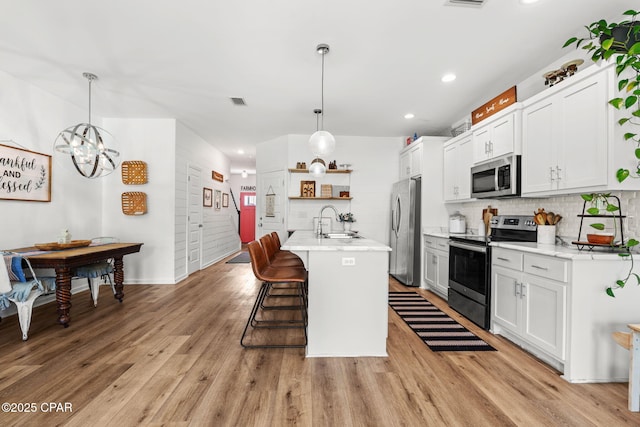 406 Raven Ln, Panama City, FL 32404 - kitchen featuring stainless steel appliances, open shelves, decorative backsplash, a kitchen bar, and light wood-type flooring