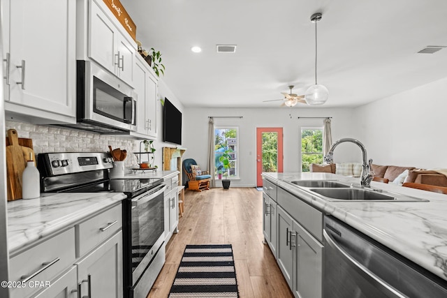 406 Raven Ln, Panama City, FL 32404 - kitchen with appliances with stainless steel finishes, decorative backsplash, light wood-type flooring, ceiling fan, and light stone counters