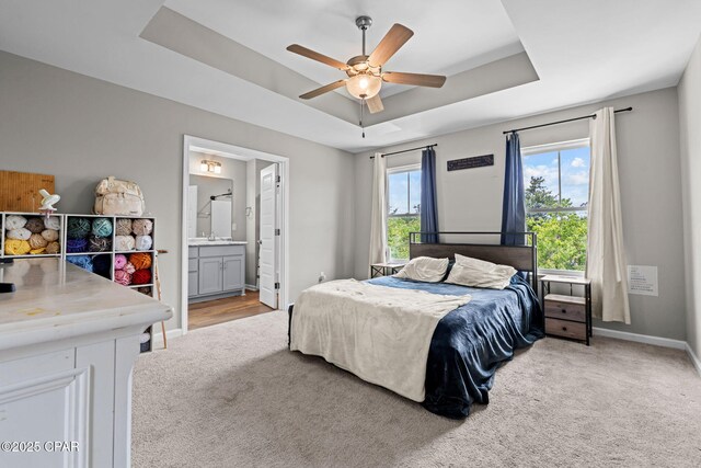 406 Raven Ln, Panama City, FL 32404 - bedroom with light colored carpet, a raised ceiling, connected bathroom, and a ceiling fan