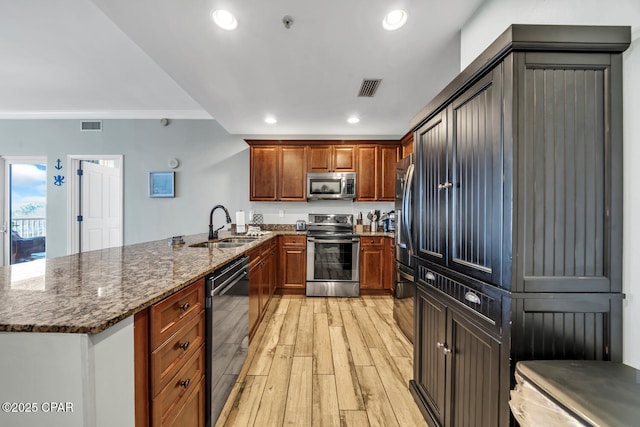 4100 Marriott Dr Unit 402, Panama City Beach, FL 32408 - kitchen with appliances with stainless steel finishes, a peninsula, crown molding, dark stone countertops, and light wood-style floors
