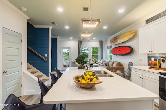 21818 Kelly Pines Pl, Panama City Beach, FL 32413 - kitchen featuring crown molding, a center island with sink, white cabinetry, open floor plan, and decorative backsplash
