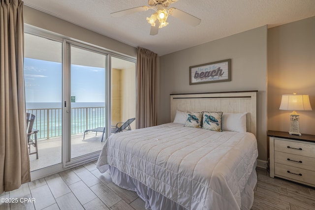 10625 Front Beach Rd Unit 1102, Panama City Beach, FL 32407 - bedroom with access to exterior, a textured ceiling, ceiling fan, a water view, and wood finished floors