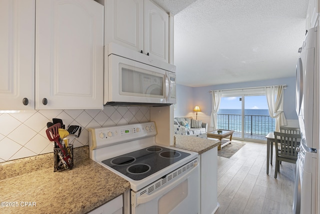 8743 Thomas Dr Unit 928, Panama City Beach, FL 32408 - kitchen with white appliances, white cabinetry, a water view, light wood-style flooring, and a textured ceiling