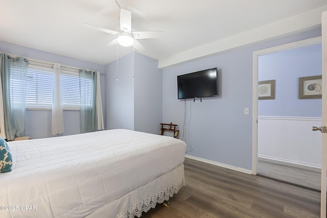 8743 Thomas Dr Unit 928, Panama City Beach, FL 32408 - bedroom with dark wood-style flooring, a ceiling fan, and wainscoting