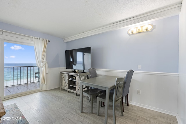 8743 Thomas Dr Unit 928, Panama City Beach, FL 32408 - dining space with wainscoting, wood finished floors, a chandelier, and a textured ceiling