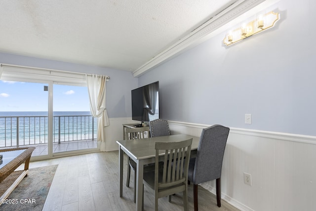 8743 Thomas Dr Unit 928, Panama City Beach, FL 32408 - dining room with wainscoting, wood finished floors, and a textured ceiling
