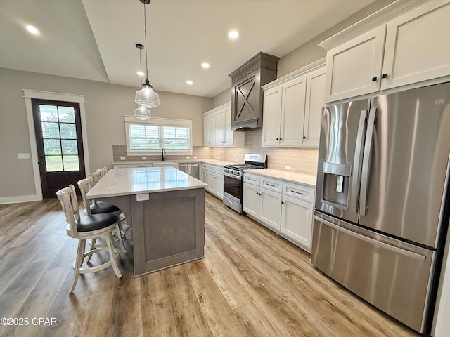 3391 Grey Oak Way, Marianna, FL 32446 - kitchen featuring appliances with stainless steel finishes, backsplash, a center island, light wood-style flooring, and white cabinets
