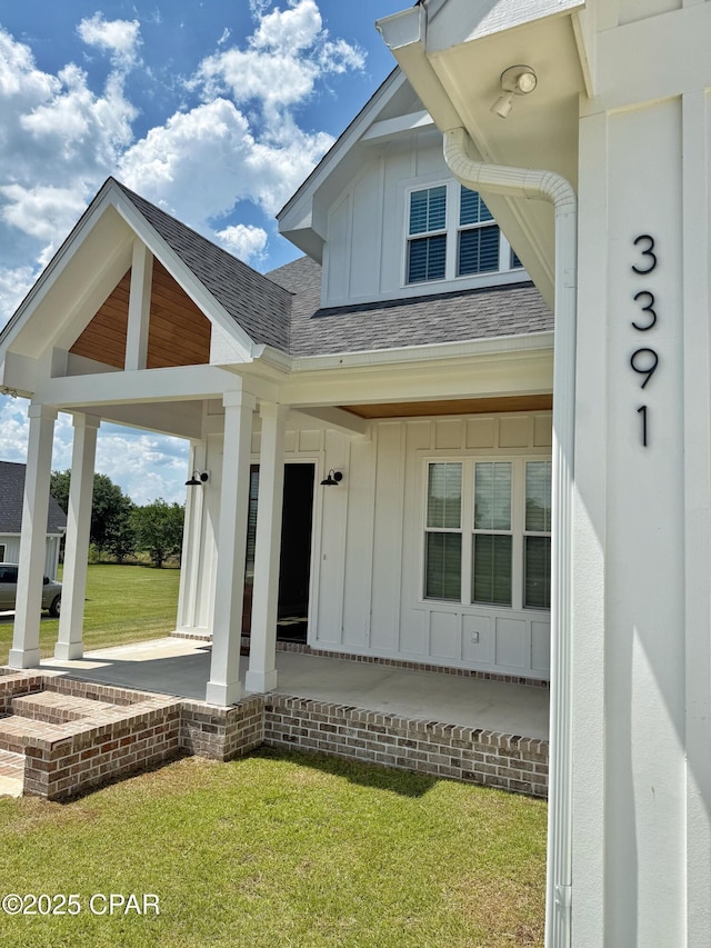 3391 Grey Oak Way, Marianna, FL 32446 - view of exterior entry featuring board and batten siding, roof with shingles, covered porch, and a lawn