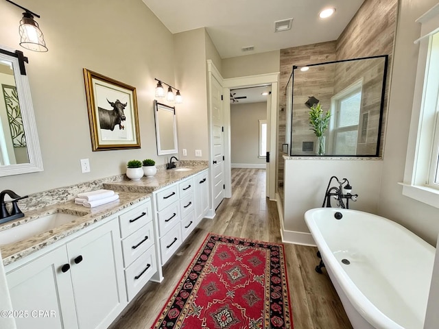 3391 Grey Oak Way, Marianna, FL 32446 - bathroom featuring double vanity, a shower stall, a freestanding tub, and wood finished floors