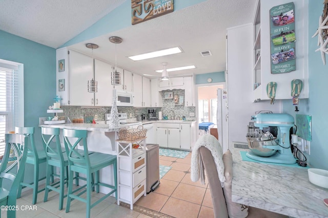101 Gulf Loop, Panama City Beach, FL 32408 - kitchen featuring white appliances, tasteful backsplash, a peninsula, white cabinets, and a textured ceiling