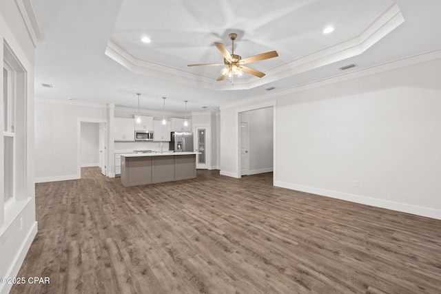 902 Captain Way, Panama City, FL 32404 - unfurnished living room with a tray ceiling, ornamental molding, recessed lighting, dark wood finished floors, and a ceiling fan