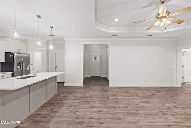 902 Captain Way, Panama City, FL 32404 - kitchen featuring stainless steel fridge, crown molding, wood finished floors, white cabinetry, and light countertops