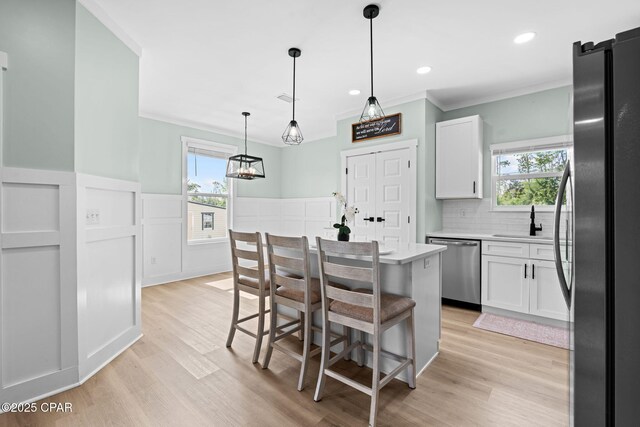 8422 Resota Beach Rd, Southport, FL 32409 - kitchen with stainless steel appliances, ornamental molding, light wood finished floors, white cabinetry, and light countertops