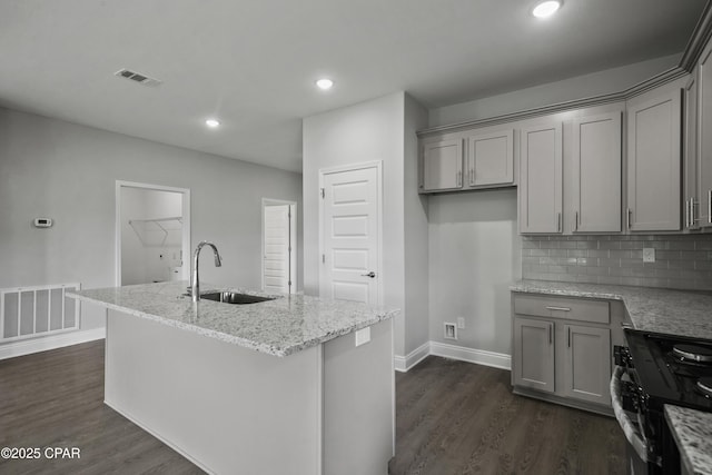 237 Mosaic Dr Unit 42, Port St Joe, FL 32456 - kitchen featuring black gas range oven, gray cabinets, dark wood-type flooring, light stone counters, and a center island with sink