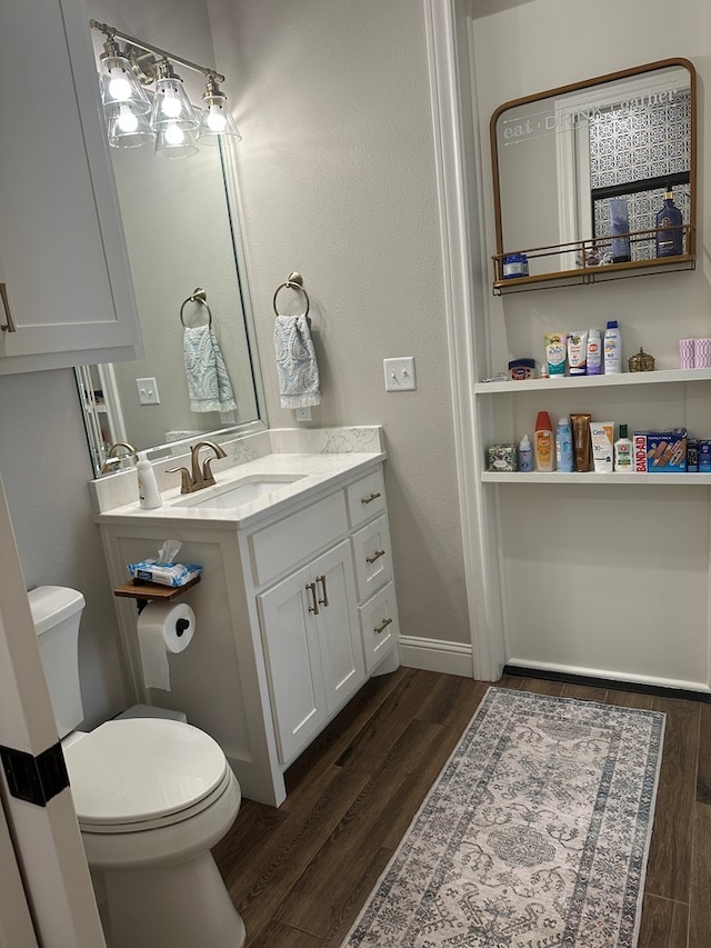 1733 Overhill Dr, San Angelo, TX 76904 - bathroom featuring wood finished floors, toilet, vanity, and baseboards