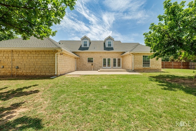 rear view of property featuring a patio area, a shingled roof, a lawn, fence, and french doors