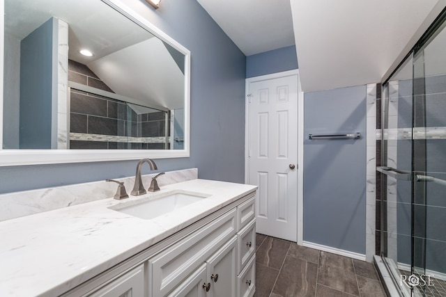 full bath featuring a stall shower, lofted ceiling, vanity, and baseboards