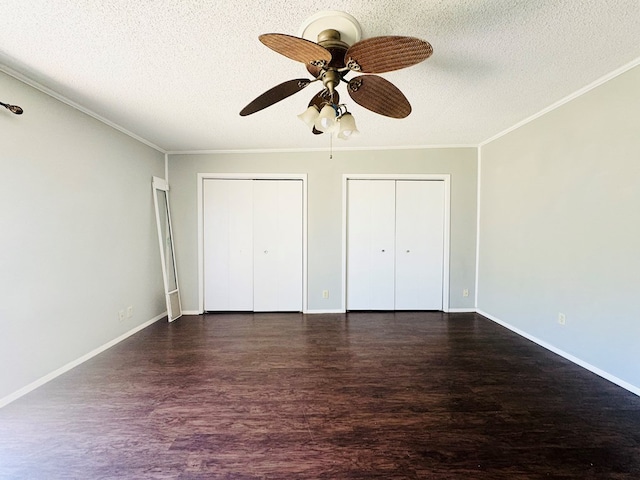 unfurnished bedroom with ceiling fan, dark hardwood / wood-style floors, a textured ceiling, and two closets