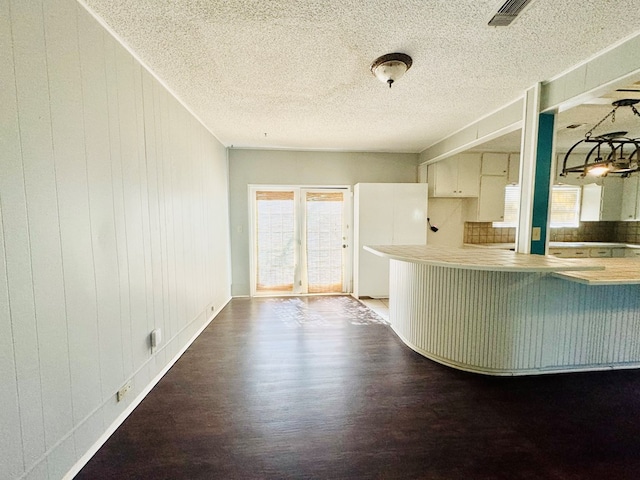 kitchen featuring a healthy amount of sunlight, wooden walls, and wood-type flooring