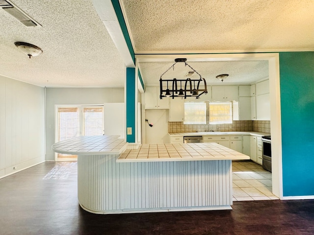 kitchen featuring appliances with stainless steel finishes, tile countertops, decorative light fixtures, white cabinetry, and kitchen peninsula