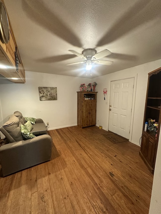 living room featuring ceiling fan, wood-type flooring, and a textured ceiling