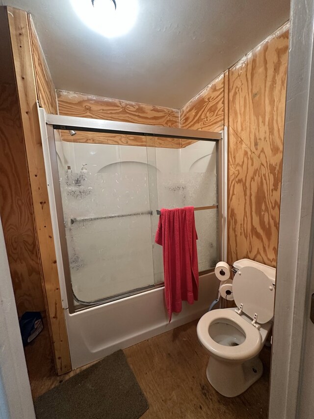 bathroom with toilet, wood-type flooring, and shower / bath combination with glass door