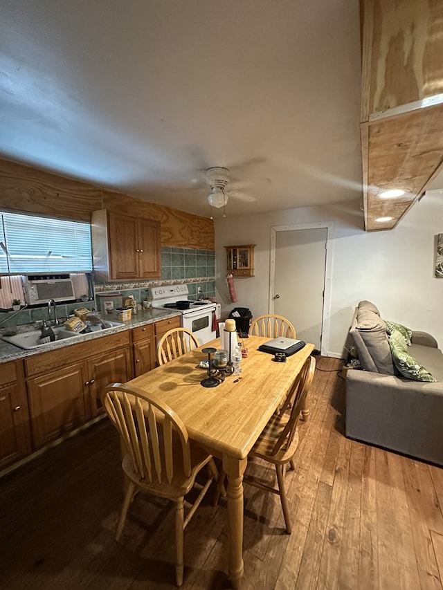 dining area featuring sink, wood-type flooring, and ceiling fan