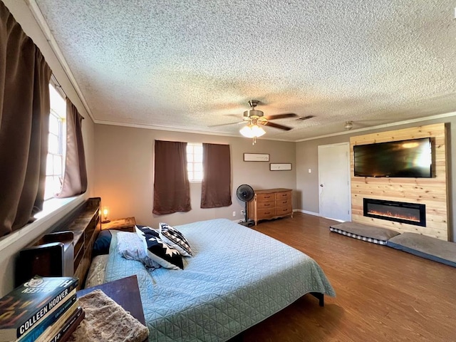 bedroom featuring a textured ceiling, ornamental molding, ceiling fan, a fireplace, and hardwood / wood-style floors