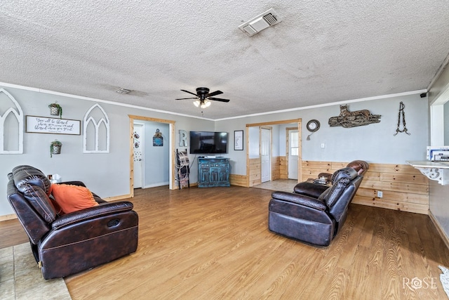 living room featuring crown molding, wood-type flooring, ceiling fan, and a textured ceiling