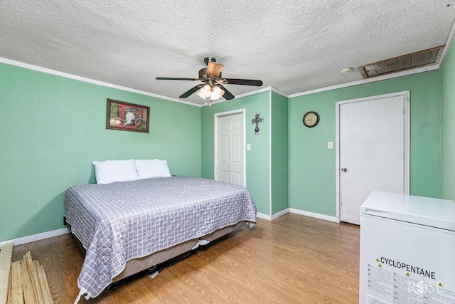 bedroom with refrigerator, wood-type flooring, ceiling fan, crown molding, and a textured ceiling