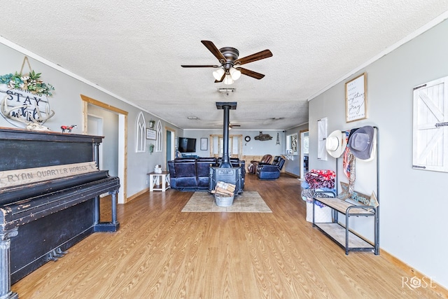 living room with ornamental molding, hardwood / wood-style floors, a textured ceiling, and a wood stove