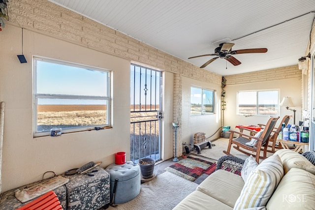 carpeted living room with a water view and ceiling fan