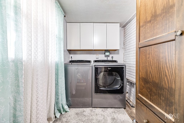 clothes washing area featuring cabinets, a textured ceiling, and washer and clothes dryer