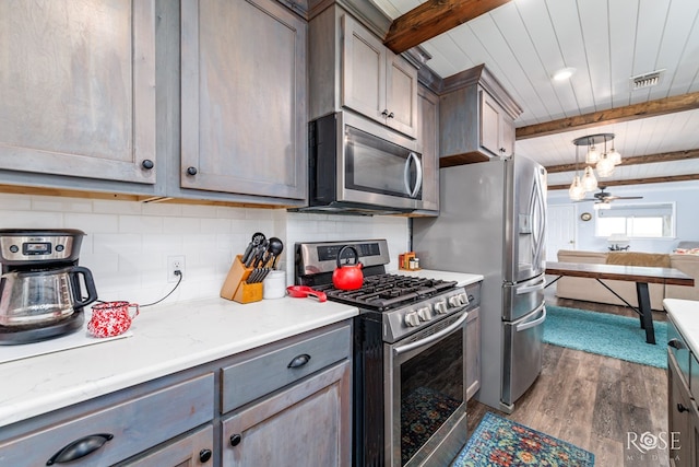 kitchen featuring tasteful backsplash, wood-type flooring, beamed ceiling, ceiling fan, and stainless steel appliances