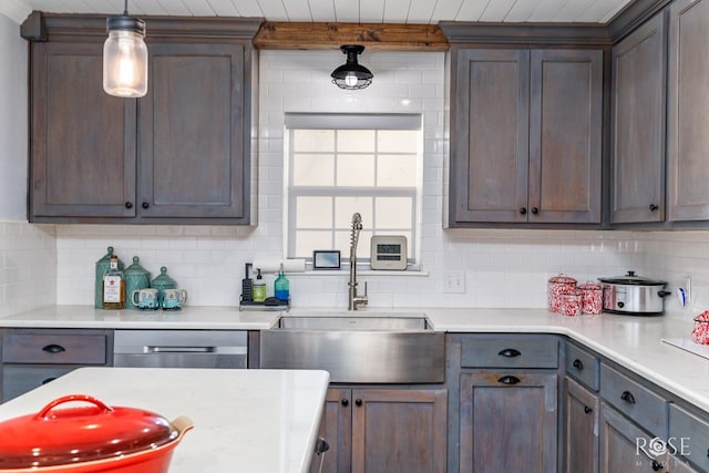 kitchen featuring tasteful backsplash, sink, dark brown cabinetry, and decorative light fixtures