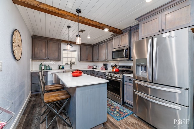 kitchen featuring pendant lighting, beamed ceiling, dark hardwood / wood-style flooring, a center island, and stainless steel appliances