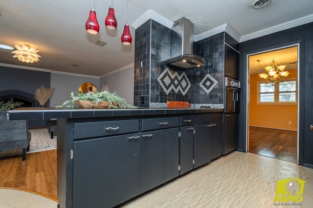 2720 Tanglewood Dr, San Angelo, TX 76904 - kitchen with wall chimney range hood, black oven, a textured ceiling, light wood-type flooring, and a chandelier