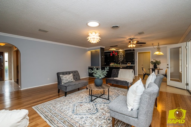 2720 Tanglewood Dr, San Angelo, TX 76904 - living room featuring arched walkways, a textured ceiling, ornamental molding, baseboards, and a ceiling fan