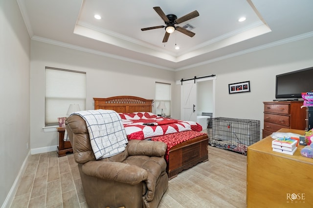 bedroom with a tray ceiling, ornamental molding, light hardwood / wood-style flooring, and a barn door