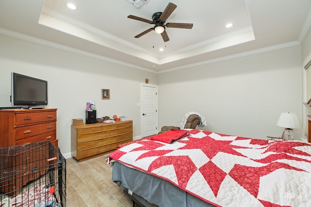 bedroom with a tray ceiling, ornamental molding, ceiling fan, and light hardwood / wood-style flooring