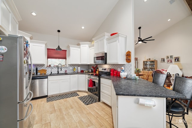 kitchen with sink, a breakfast bar, decorative light fixtures, stainless steel appliances, and kitchen peninsula