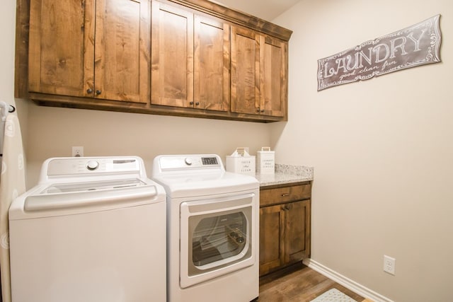 clothes washing area with separate washer and dryer, dark hardwood / wood-style flooring, and cabinets