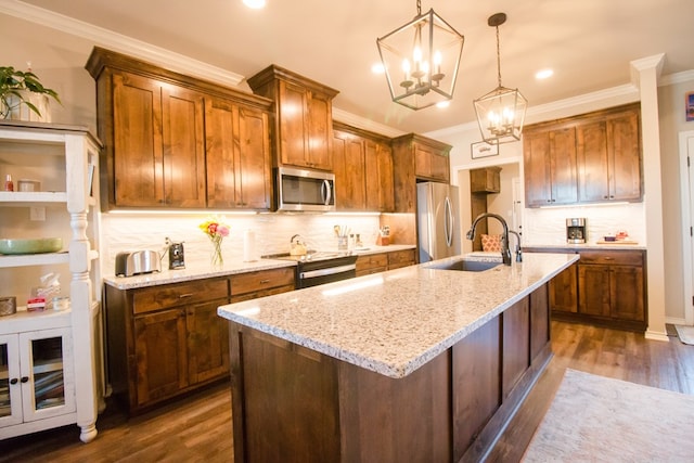 kitchen with light stone counters, hanging light fixtures, stainless steel appliances, and a center island with sink