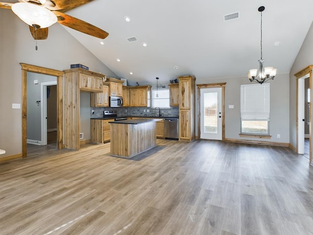 kitchen featuring stainless steel appliances, a center island, decorative backsplash, and decorative light fixtures