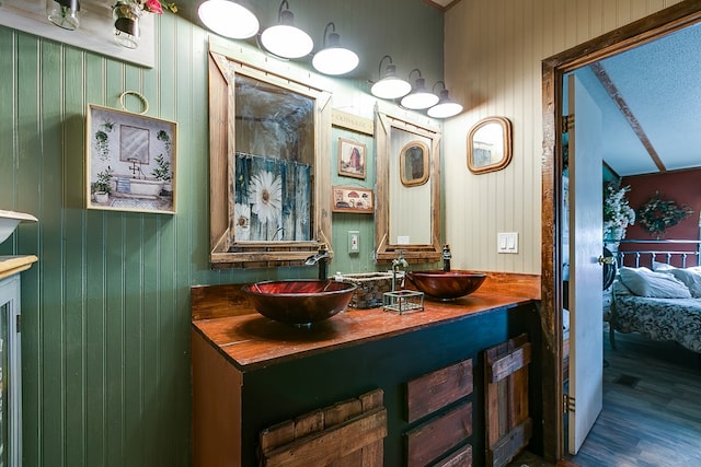 ensuite bathroom with a sink, double vanity, ensuite bath, and wood finished floors