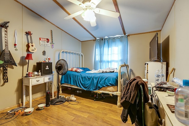 bedroom with a ceiling fan, wood finished floors, ornamental molding, and vaulted ceiling