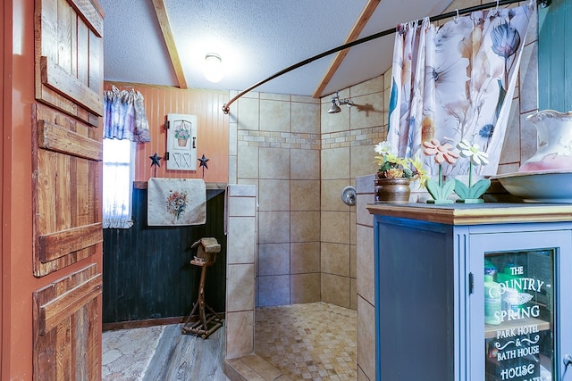 full bath featuring a tile shower, lofted ceiling, and a textured ceiling