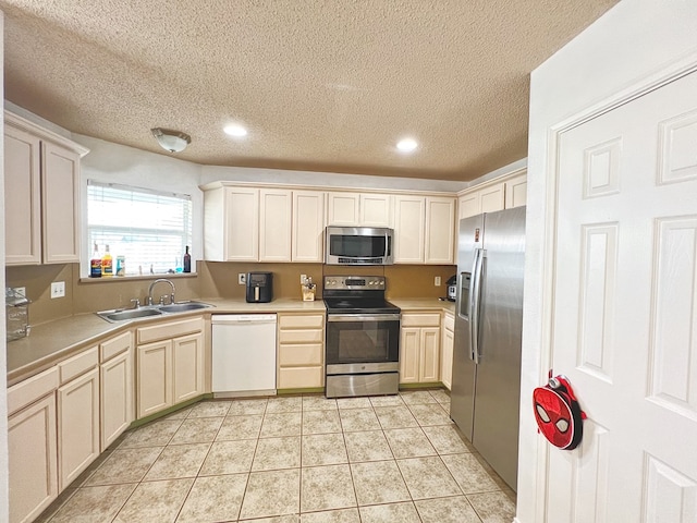 kitchen featuring sink, light tile patterned floors, stainless steel appliances, and a textured ceiling